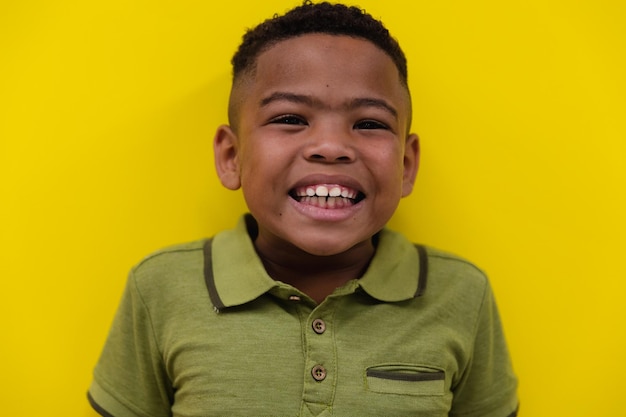 Close-up portrait of smiling african american elementary schoolboy against yellow wall