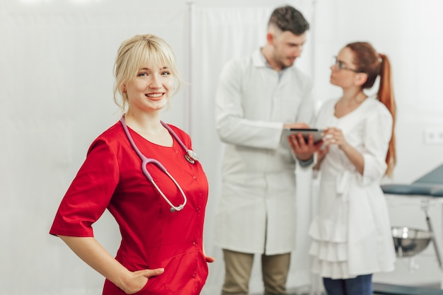 Close-up portrait of a smiling female doctor in a red uniform with a stethoscope