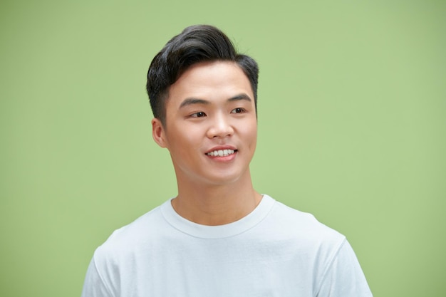 Close up portrait of smiling handsome man in white tshirt looking at camera isolated on green background