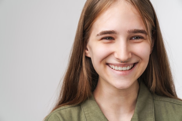 Close up portrait of a smiling pretty young girl with long blonde hair standing 