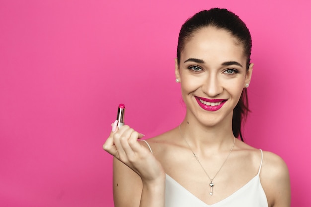 Close up portrait of smiling woman with a ponytail on a pink background