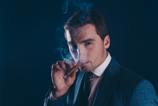 Close up portrait of stunning man smoking cigar