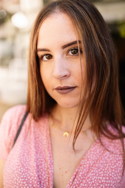 Close up portrait of stylish pensive young woman with intense gaze in the street. Summer fashion trend, cheerful, positive. Hair movement. Lifestyle concept.