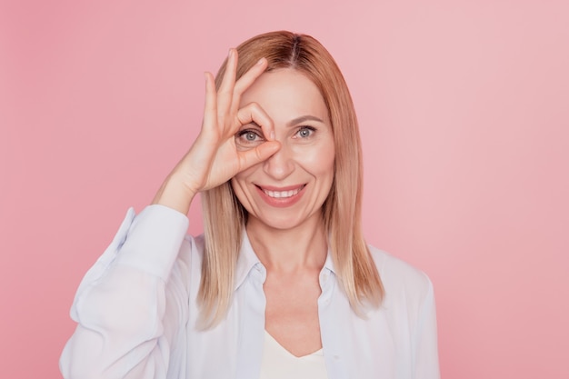 Close up portrait of sweet cute girl gesturing ok sign eye binoculars fingers perfect isolated on pink background