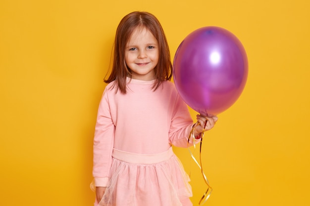 Close up portrait of sweet nice girl with purple balloon in hands.