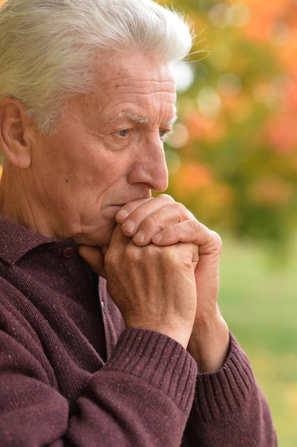 Close up portrait of thoughtful senior man in autumn park