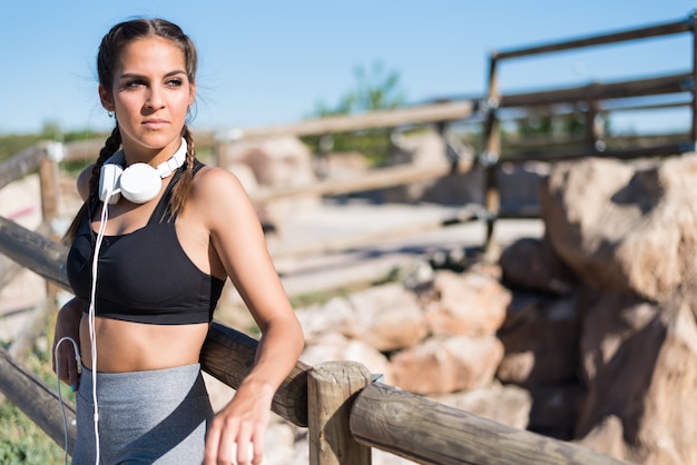 Close up portrait of a woman doing sport resting outdoor smiling and listening music 
