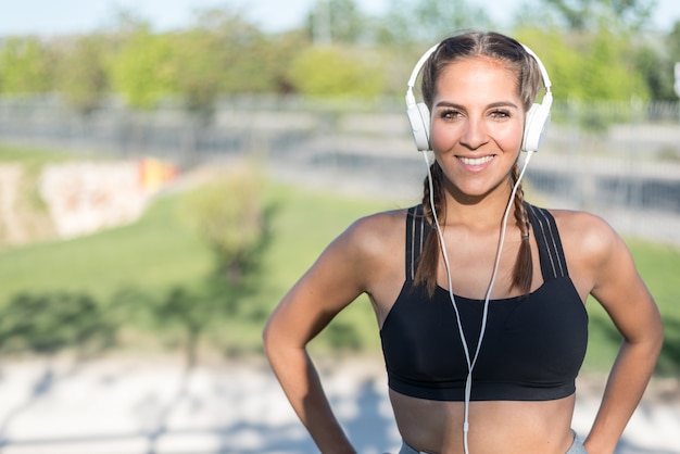 Close up portrait of a woman doing sport resting outdoor smiling and listening music 
