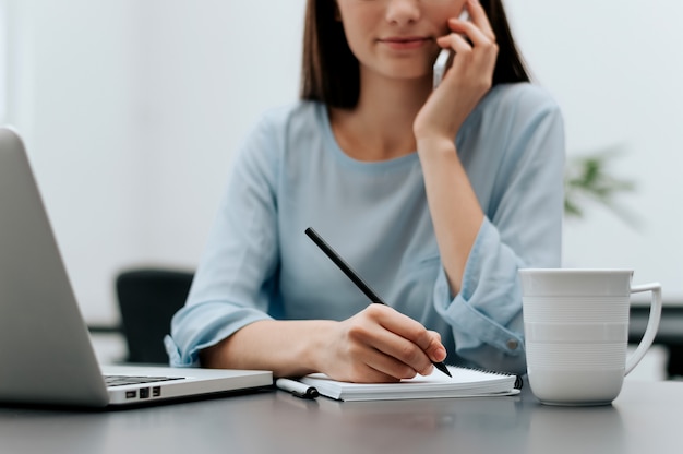 Close up portrait of woman on her phone, taking notes.