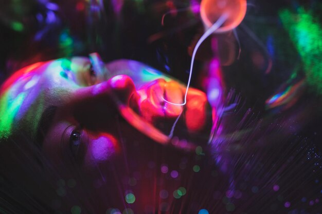 Photo close-up portrait of woman with illuminated bulb and fiber optic in nightclub