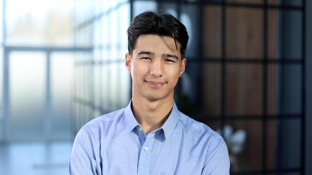 Close up portrait of young asian businessman standing in empty office