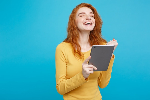 Close up Portrait young beautiful attractive redhair girl happy smiling on digital table with wining something. Blue Pastel Background. Copy space.