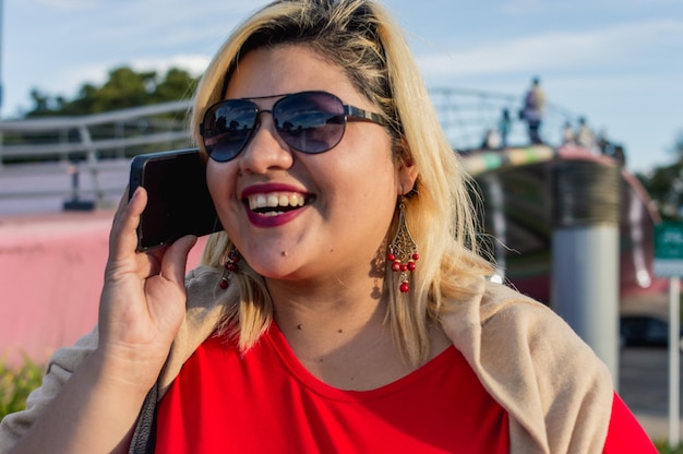 Close up portrait young caucasian latin woman smiling talking on the phone outdoors