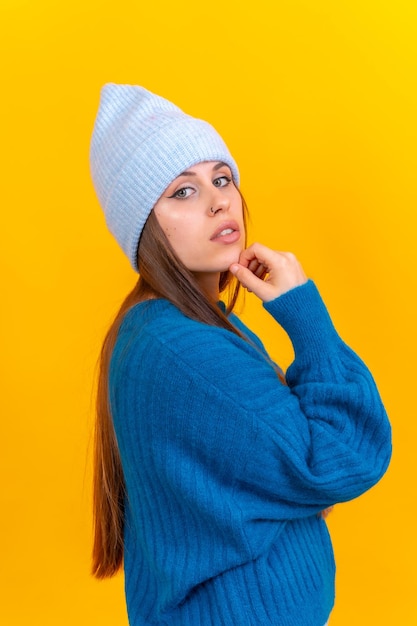 Close up portrait of young caucasian woman in blue wool sweater isolated on yellow background in studio