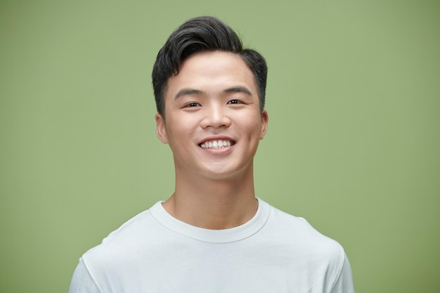 Close up portrait of young handsome Asian man cheerfuly smiling and looking at camera