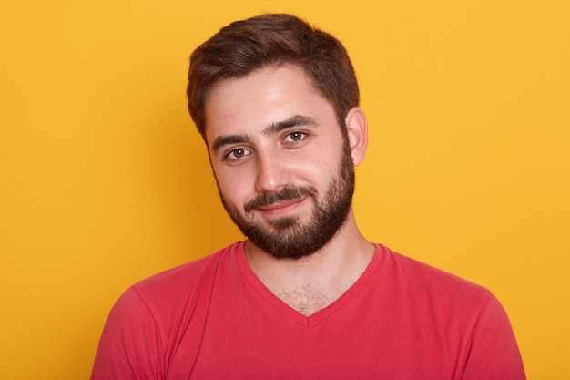 Close up portrait of young handsome man with beard wearing red casual t shirt