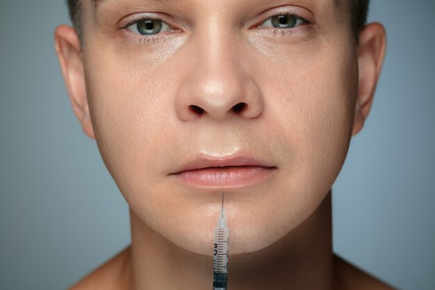 Photo close-up portrait of young man isolated on grey wall