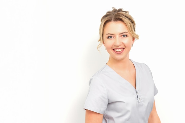 Close-up portrait of a young smiling female caucasian healthcare worker standing staring