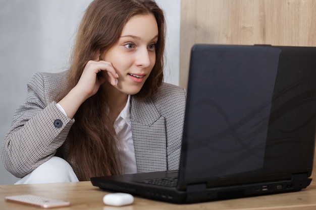 Close up portrait of a young surprised girl looking at laptop