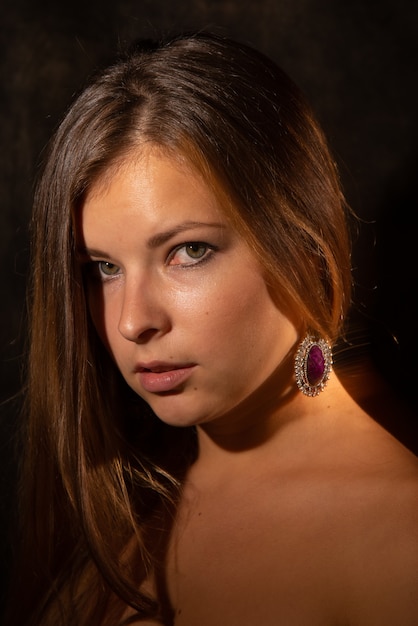 Close-up portrait of young woman in mixed light against dark background