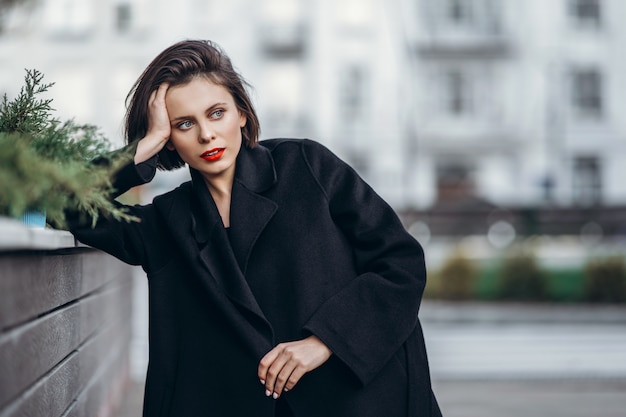 Close up portrait of young woman with short haircut and red lips outdoors