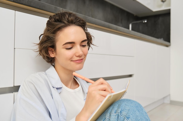 Close up portrait of young woman writing in her journal feeling creative sitting with planner notebo