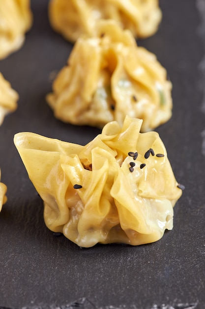 Close-up of prawn siu mai on black plate.