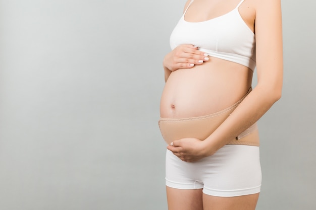 Close up of pregnancy bandage dressed on pregnant woman in underwear