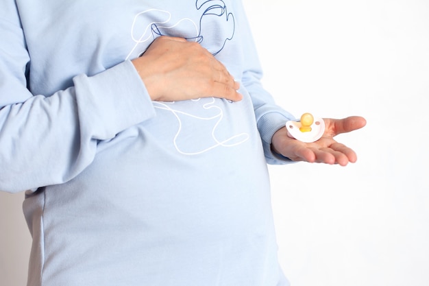 Close up of pregnant who holds a pink pacifier for a baby Waiting