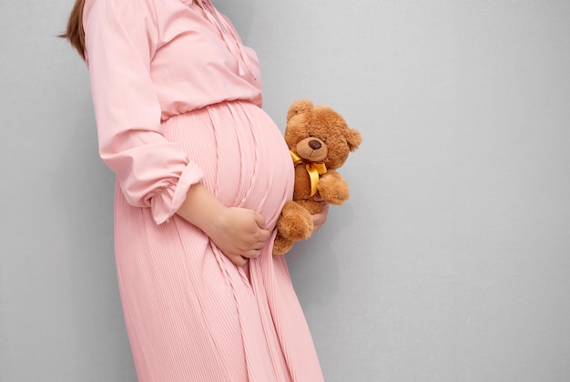 Close up of pregnant woman belly with teddy bear toyxA