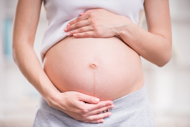 Close-up of pregnant woman keeping her hands on belly.