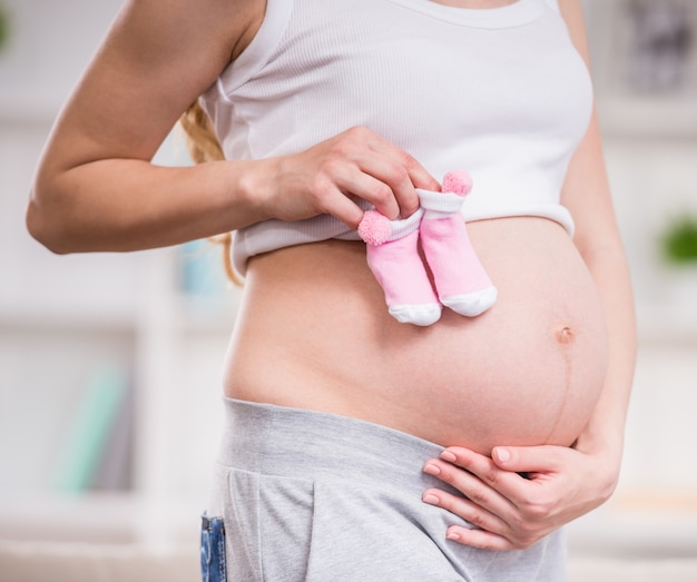 Close-up of pregnant woman keeping her hands on belly.