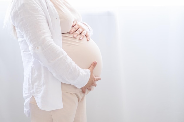 close up pregnant woman strokes her big belly. Maternity prenatal care