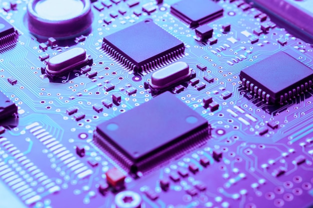 Close up of printed circuit board with electronic components toned blue and purple selective focus