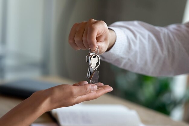 Photo close up professional realtor giving keys to client congratulating with purchasing own dwelling after signing contract agreement professional real estate services last mortgage payment concept