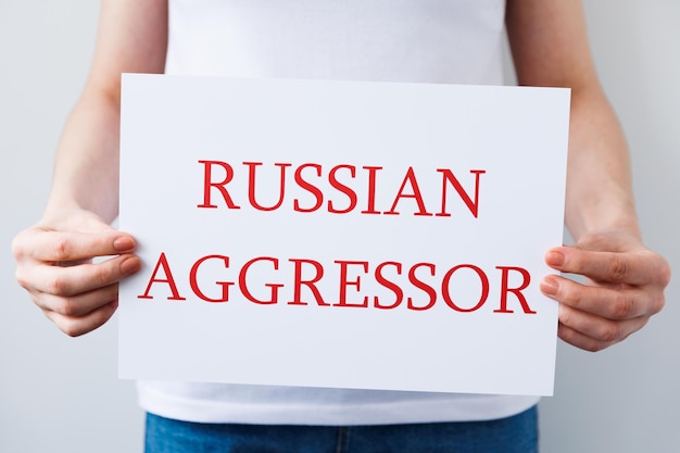 Close up of a Protester hands holding cardboard Banner with the words russian aggressor