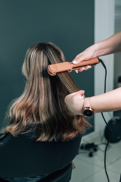 Close up Pulling strands of hair with professional ultrasonic iron tool Spa care Keratin straightening and restoration