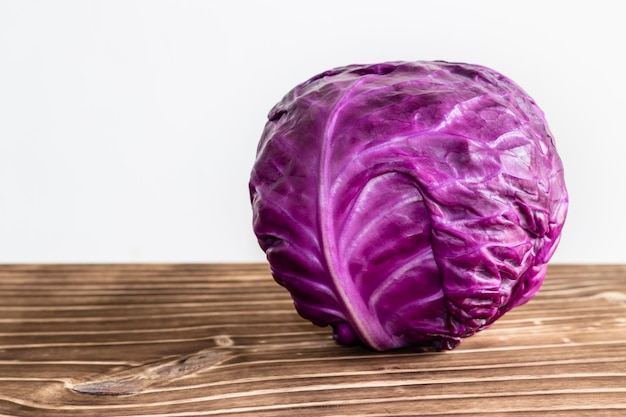 Close up on purple cabbage on wood and white background space for text