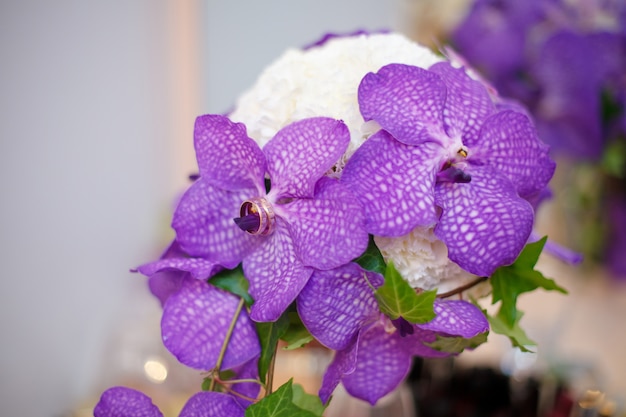 Close up of purple orchid wedding bouquet with rings