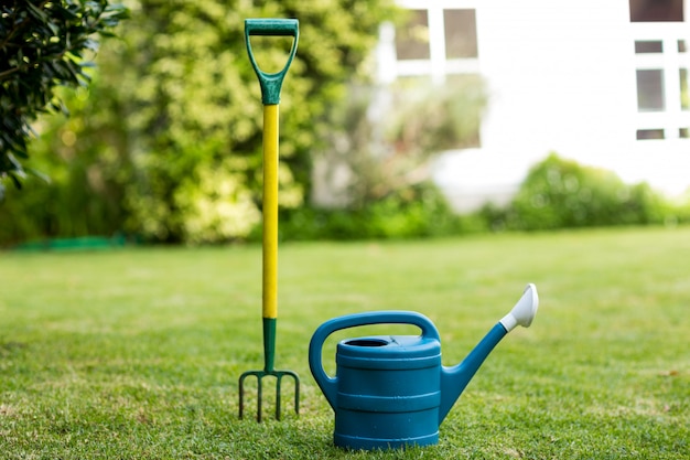 Close-up of rake and watering can in yard