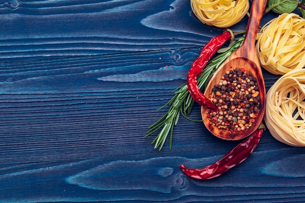 Close up of a raw dry italian pasta fettuccine on blue wooden surface 