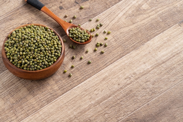 Close up of raw mung bean in a bowl on wooden table background.