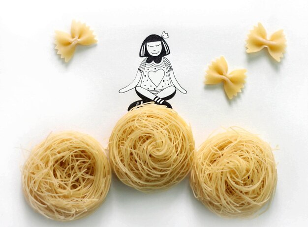 Photo close-up of raw yellow pasta and illustration of a girl sitting on it like on hay ball