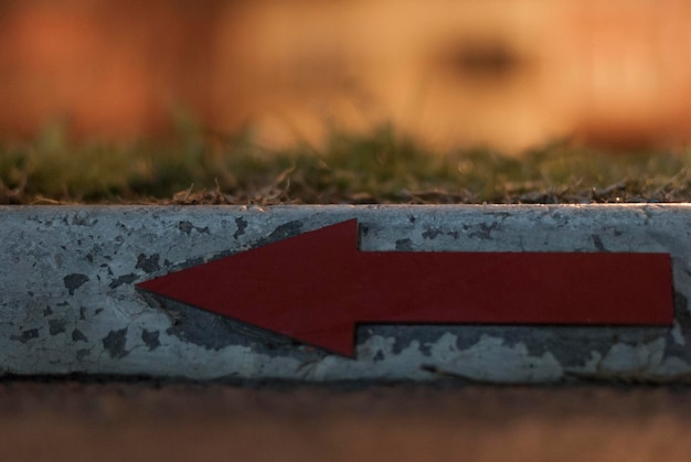 Close-up of red arrow sign on retaining wall