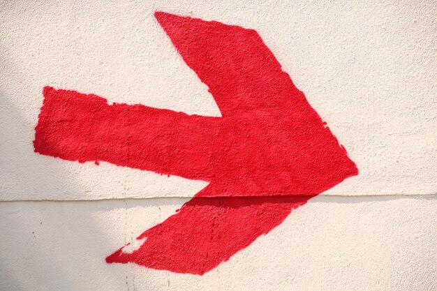 Photo close-up of red arrow symbol on wall