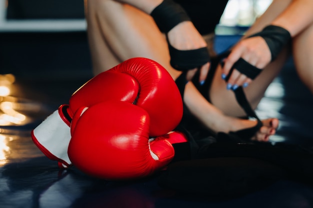 Close-up of red boxing gloves on the floor of a blue boxing ring