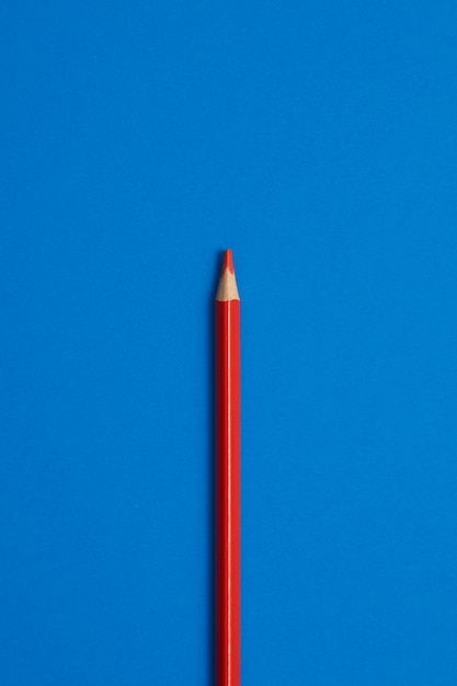 Close-up of red colored pencil isolated on blue table