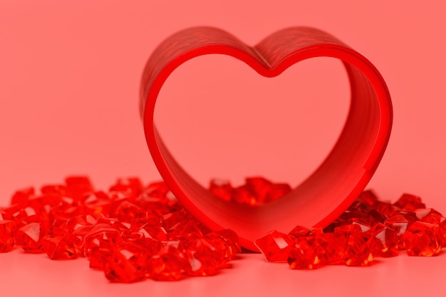 Close up red heart on a pink surface standing on the fiery red stones