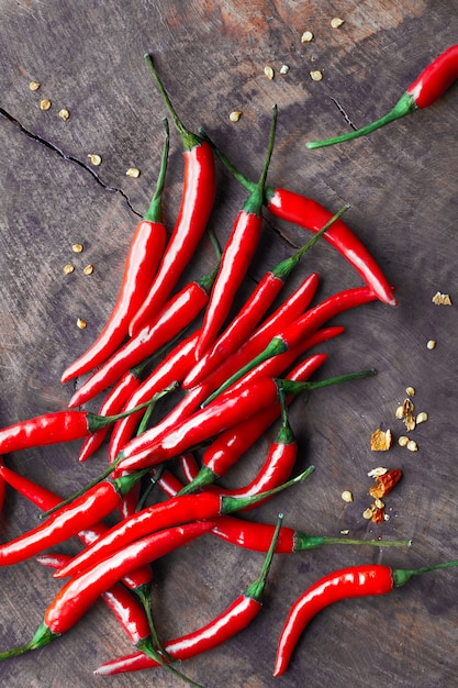 Close-up on red hot chili peppers on rustic wood, flat lay