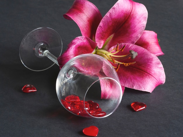 Close-up of red lily flower in a glass vase on black.